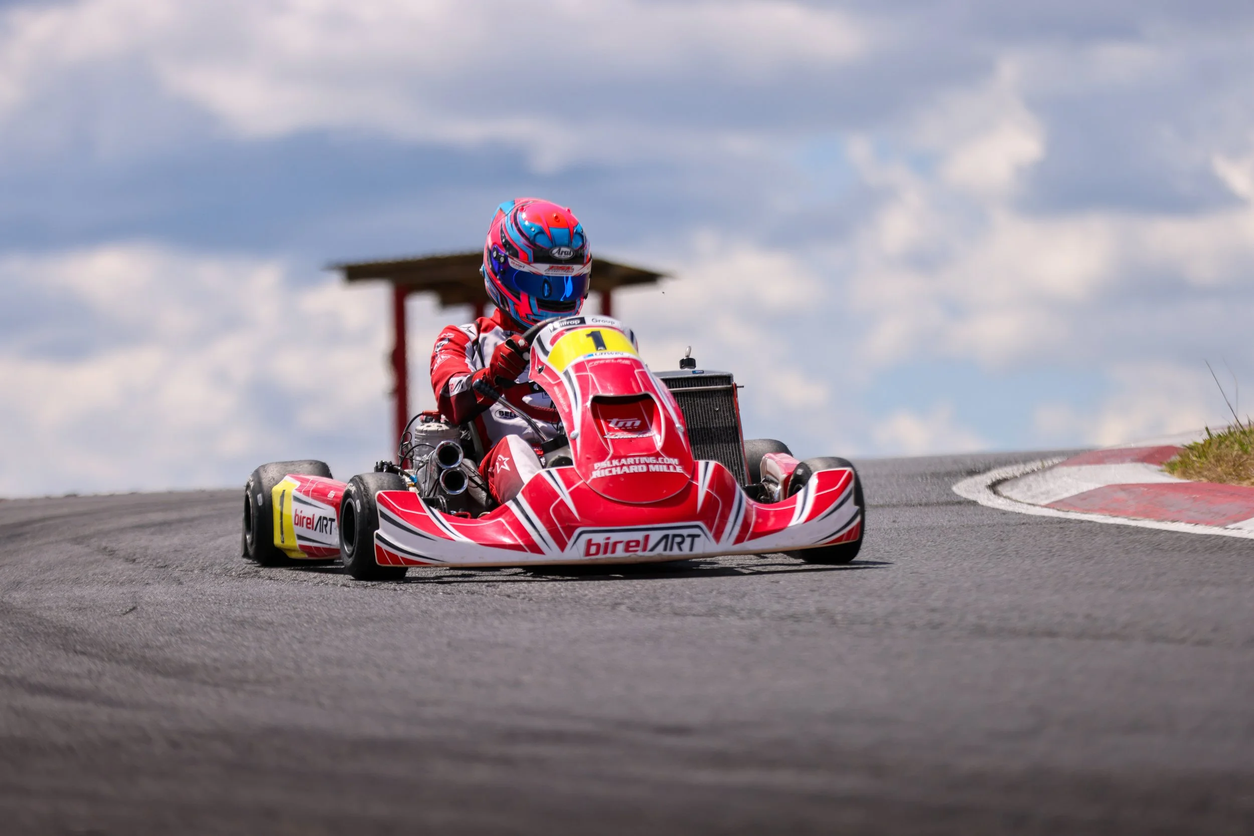 A red BirelART kart cornering hard on the Tokoroa circuit during a club race day.